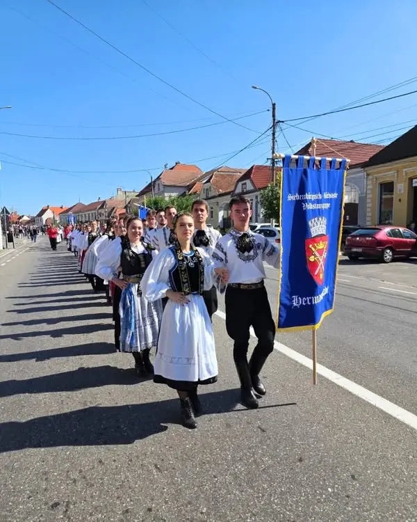 Die Hermannstädter Volkstanzgruppe beim Festumzug in Zeiden, mit Trachten und Vereinsfahne