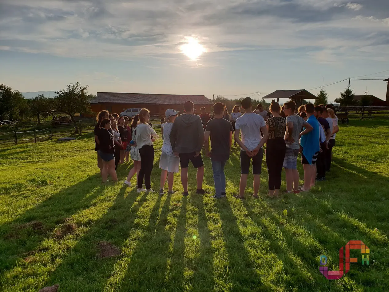 Jugendliche des DJFH stehen im Abendlicht gemeinsam im Kreis auf einer Wiese